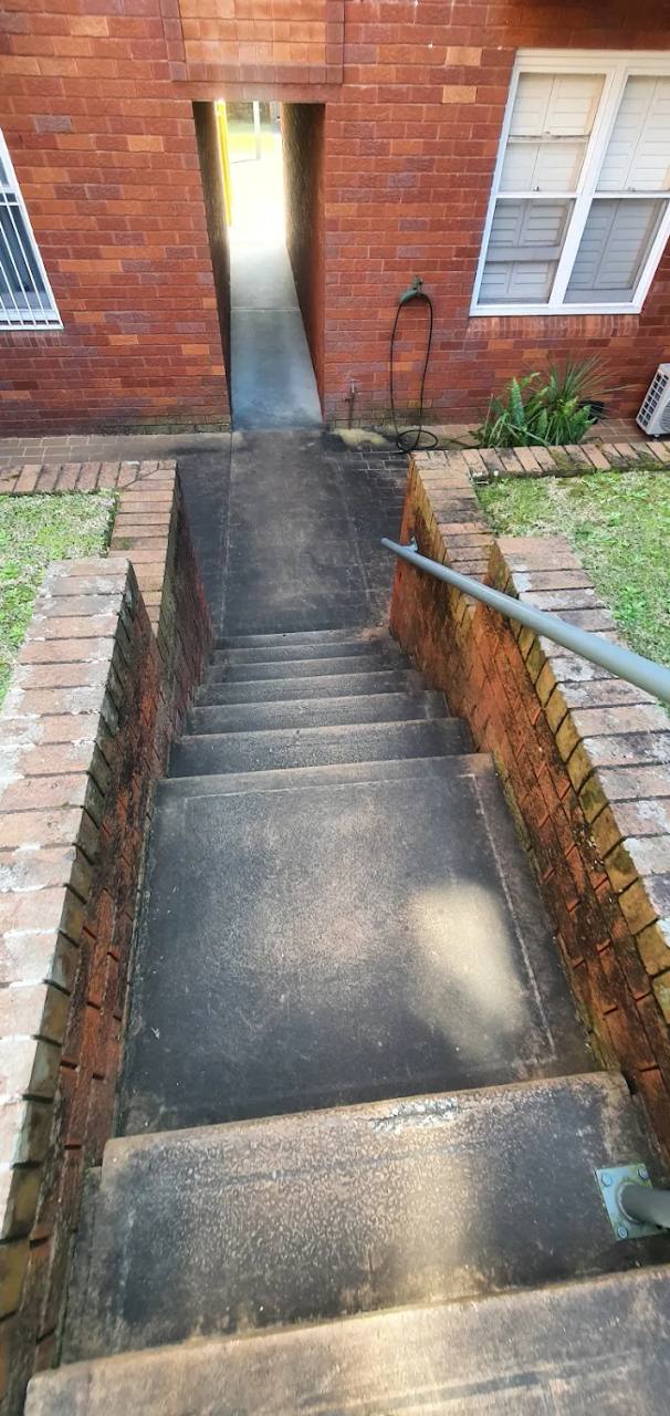 Darkened concrete stairs and courtyard before pressure cleaning