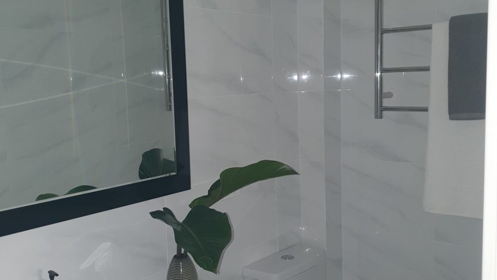 Completed Aquastar bathroom renovation with new mirror, toilet and heated towel rail