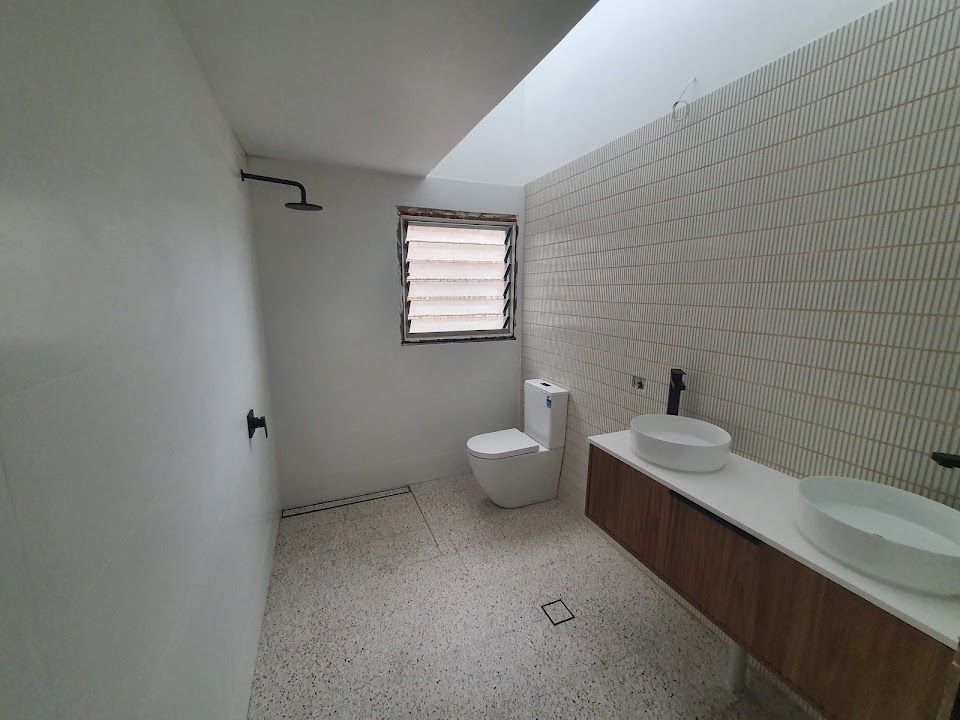 Completed bathroom plumbing renovation with a double vanity and toilet