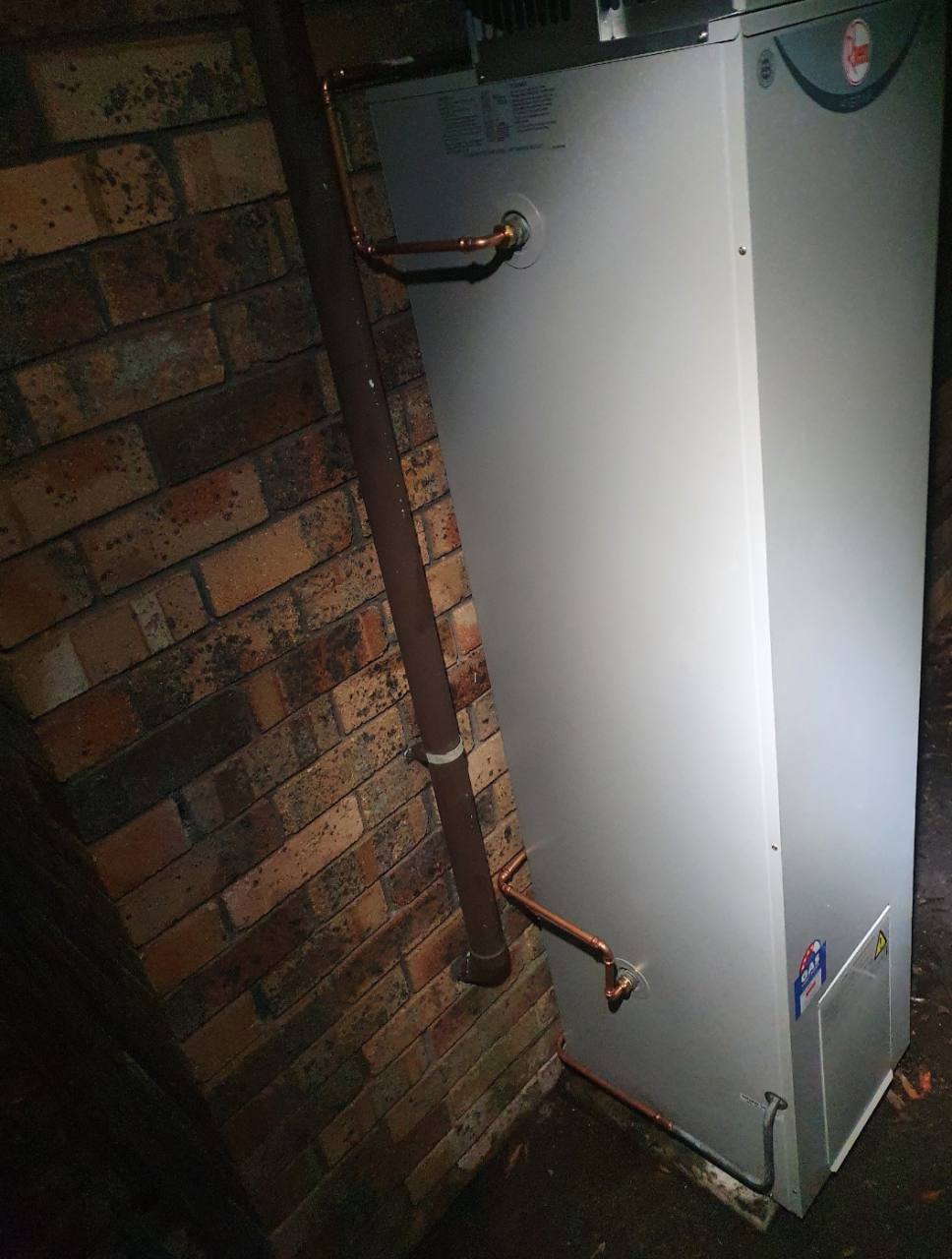 New storage hot-water system installed after dark with copper connections